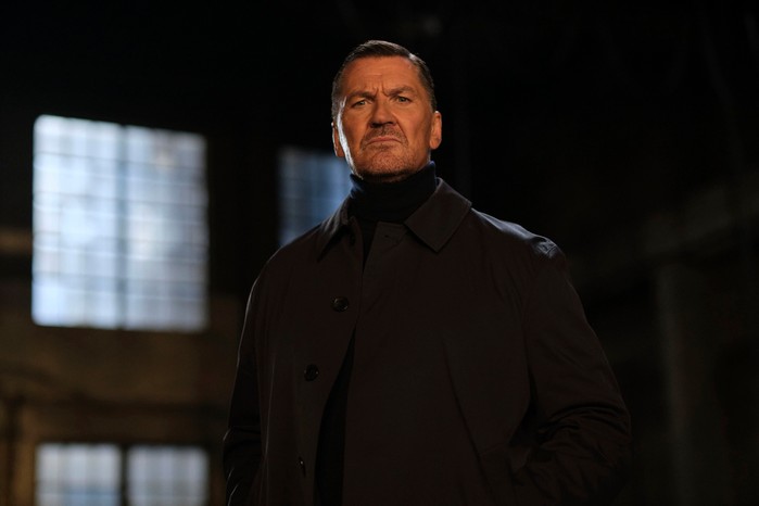 Guy (Craig Fairbrass) stands in a dark warehouse