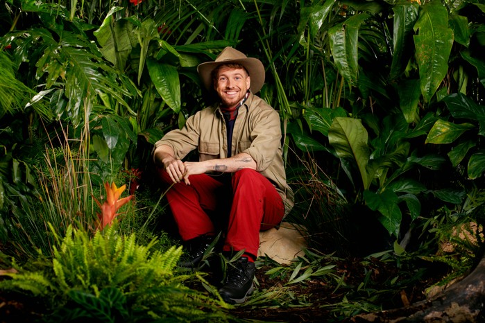 Sam-Thompson-IAC Sam Thompson dressed in his I'm a Celebrity camp gear as he poses in front of some trees ahead of the 2023 show.